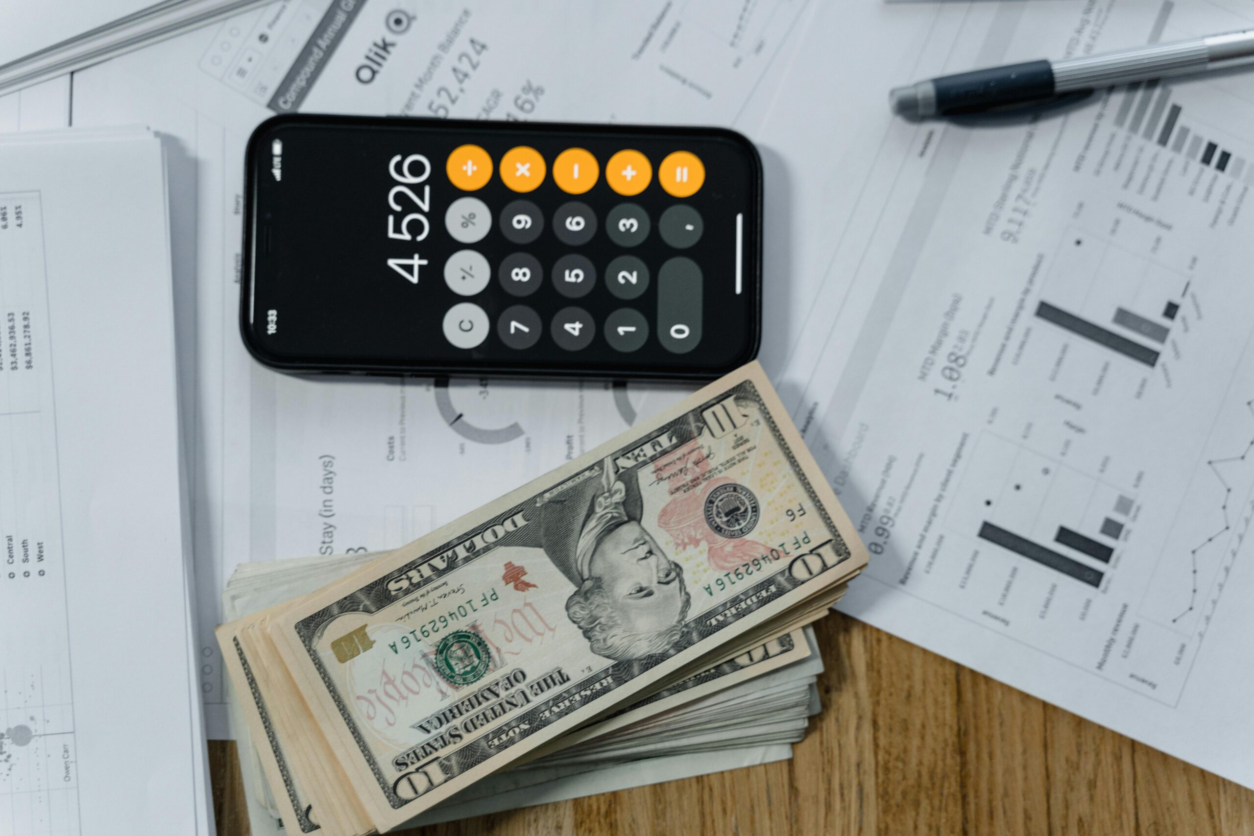 Mobile calculator, cash, and financial documents on a desk, indicating business planning.